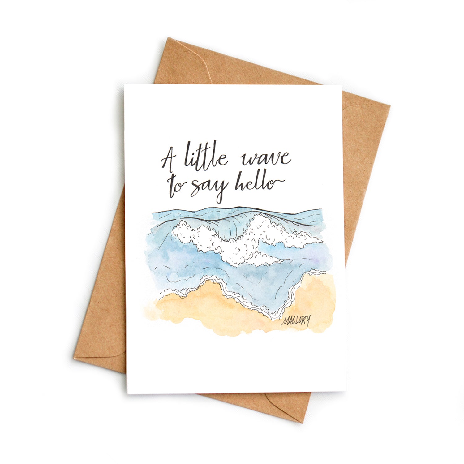 Mockup of an anytime greeting card with a handmade illustration of a wave on a beach. Written on the card is, "A little wave to say hello".