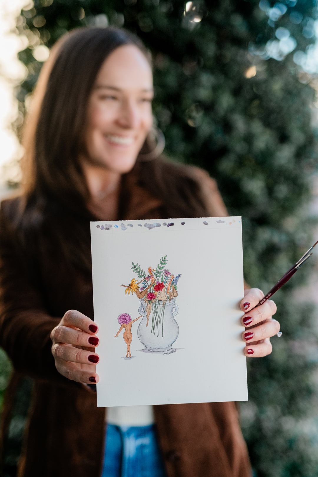 Woman holding a drawing of a vase with flowers and a person outdoors