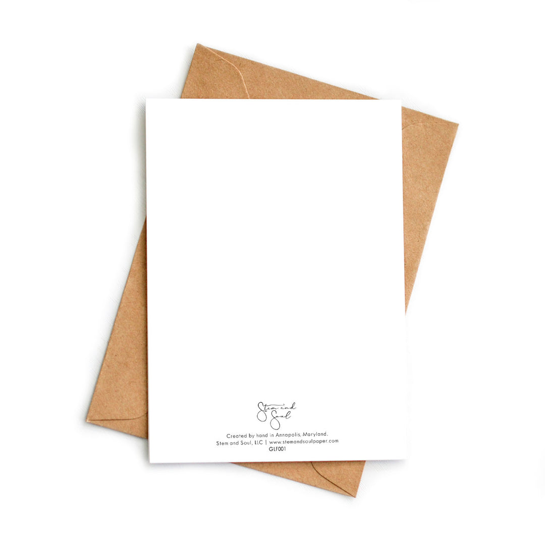 Image of the back of a white blank greeting card atop a kraft recycled envelope.