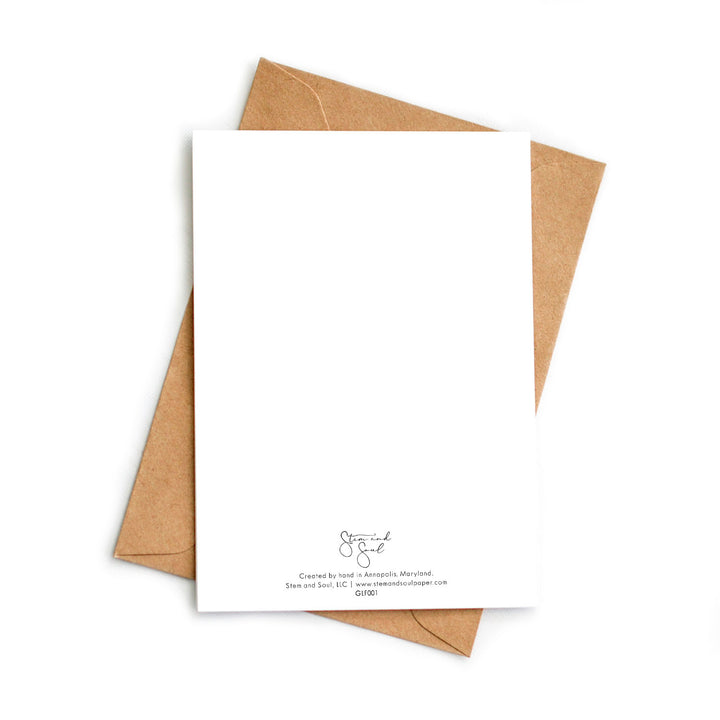 Image of the back of a white blank greeting card atop a kraft recycled envelope.