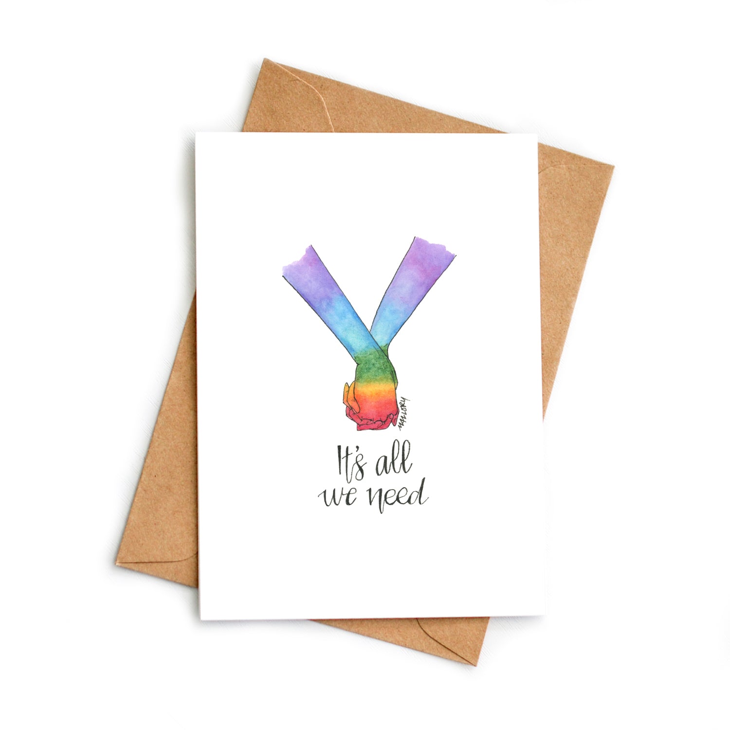 Image of a pride card to show support for LGBTQ+. Hand-drawn card shows two holding hands that are painted with the pride rainbow with the words, "It's all we need" lettered below.
