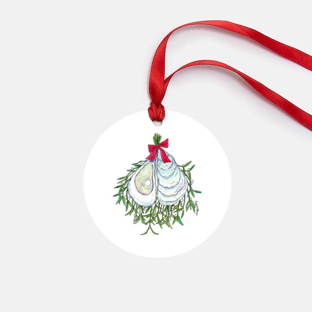 White metal Christmas tree ornament features an illustration of green mistletoe and oysters with a pearl, threaded together with a red ribbon. Ornament comes with red satin ribbon.